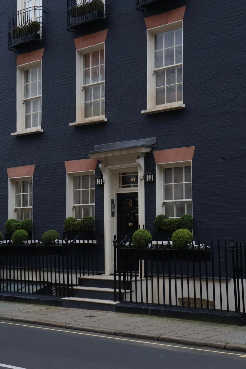 A black painted townhouse with a white door and railings