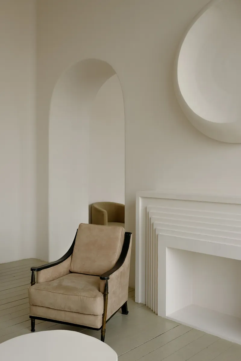 A pale armchair beside an arched niche