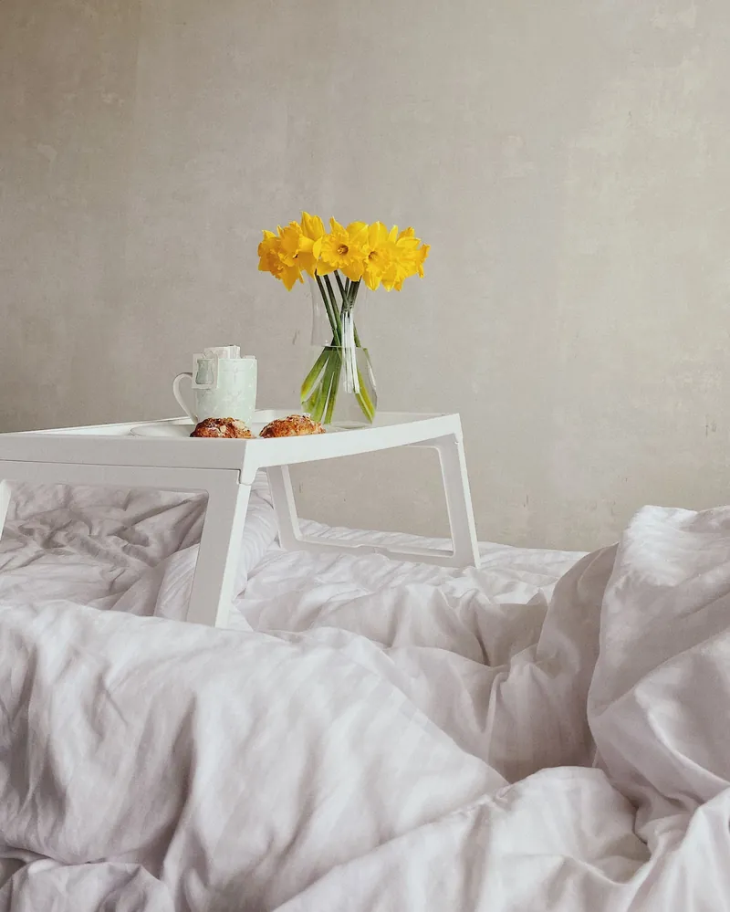 Jonquils and coffee on a tray on the bed